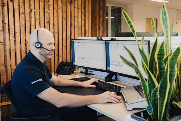 Man met headset aan de telefoon achter de computer